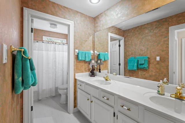 full bath featuring double vanity, a sink, toilet, and wallpapered walls