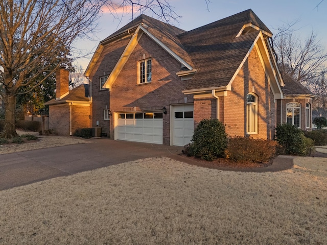 view of front facade with concrete driveway, brick siding, an attached garage, and a shingled roof