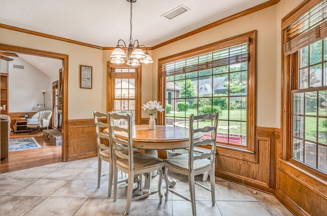 dining space featuring a wainscoted wall, visible vents, and a healthy amount of sunlight