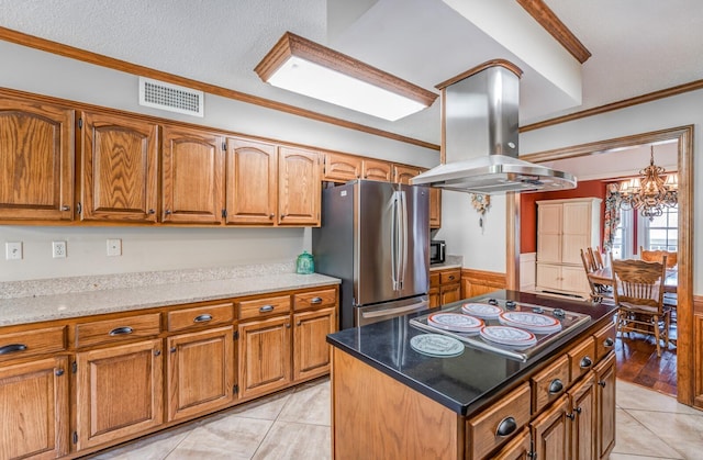 kitchen featuring electric stovetop, island exhaust hood, freestanding refrigerator, and brown cabinets