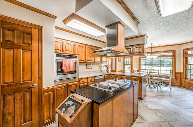 kitchen featuring island range hood, a wainscoted wall, stainless steel appliances, a peninsula, and a center island