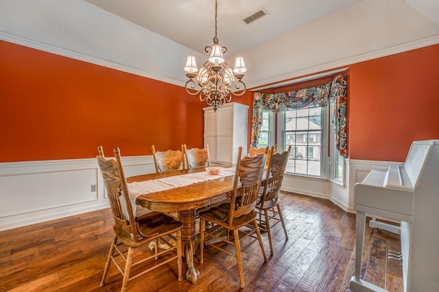 dining space featuring dark wood-style flooring, crown molding, visible vents, wainscoting, and a chandelier