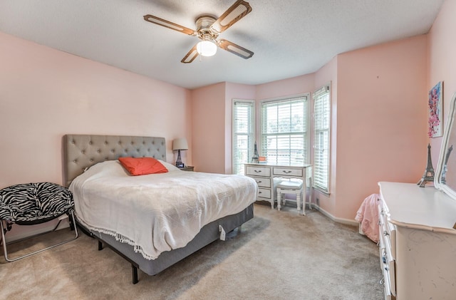 bedroom featuring light carpet, ceiling fan, and a textured ceiling