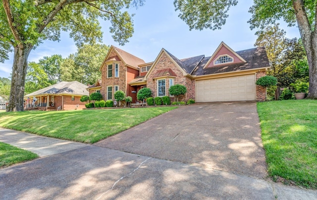 view of front of home with an attached garage, driveway, a front lawn, and brick siding