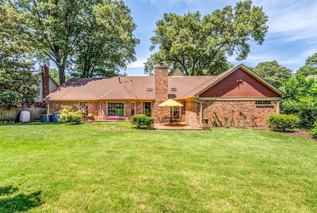 back of property with brick siding, fence, a chimney, and a lawn