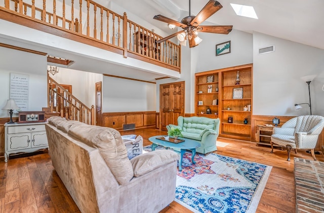 living area with a skylight, visible vents, wainscoting, wood-type flooring, and stairs