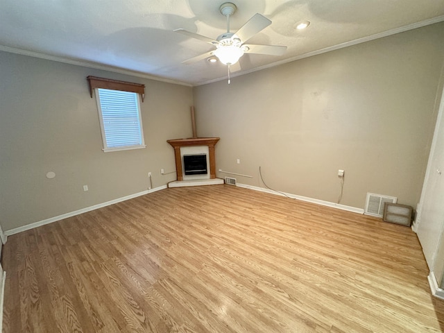 unfurnished living room featuring ornamental molding, light wood-type flooring, visible vents, and a fireplace with raised hearth