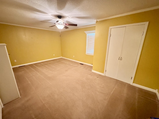 unfurnished bedroom featuring a textured ceiling, light carpet, visible vents, baseboards, and ornamental molding