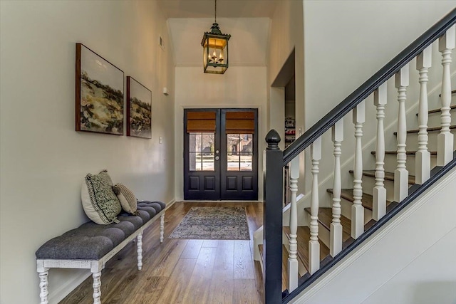 entryway featuring french doors, stairway, a high ceiling, and wood finished floors