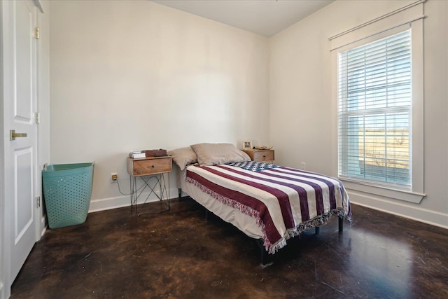 bedroom with finished concrete floors and baseboards