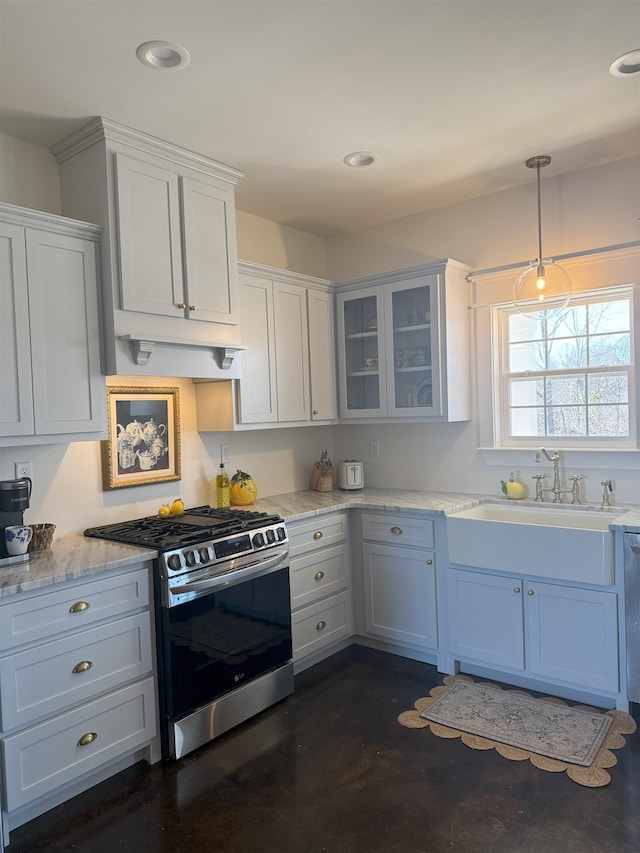 kitchen featuring glass insert cabinets, under cabinet range hood, stainless steel range with gas cooktop, a sink, and recessed lighting