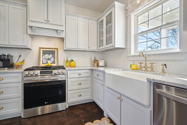 kitchen with concrete flooring, stainless steel appliances, a sink, white cabinets, and glass insert cabinets