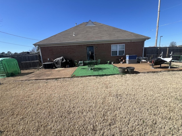 rear view of house featuring a lawn, fence, a patio, and brick siding