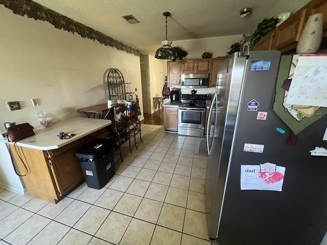 kitchen featuring visible vents, brown cabinets, stainless steel appliances, a textured ceiling, and light tile patterned flooring