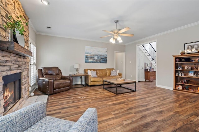 living area featuring baseboards, stairway, wood finished floors, and a stone fireplace