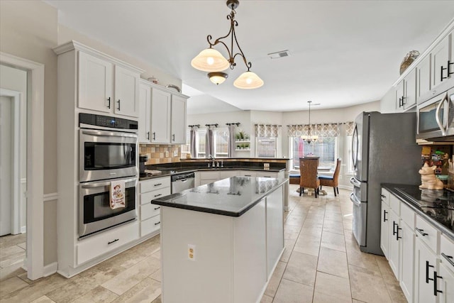 kitchen featuring tasteful backsplash, visible vents, appliances with stainless steel finishes, a peninsula, and an inviting chandelier