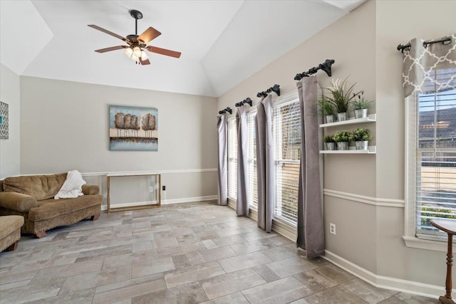 sitting room with lofted ceiling, stone finish floor, ceiling fan, and baseboards