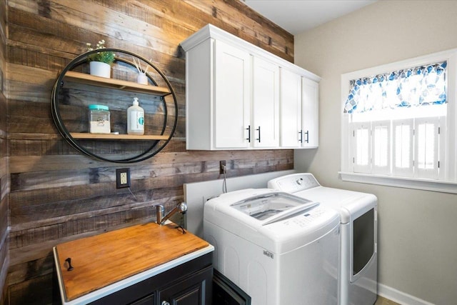 washroom featuring cabinet space, wooden walls, and separate washer and dryer