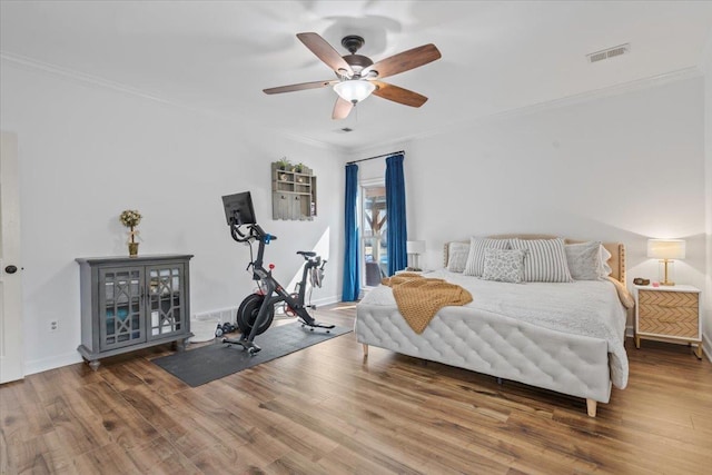 bedroom featuring baseboards, visible vents, ceiling fan, wood finished floors, and crown molding