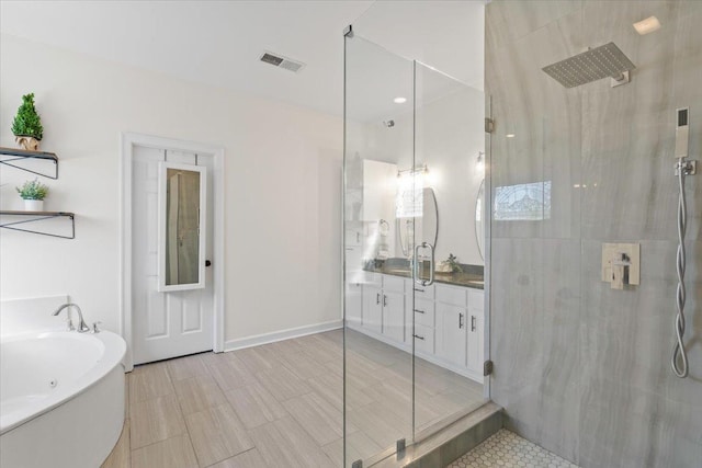 full bath featuring a tub to relax in, visible vents, a shower with shower door, vanity, and baseboards