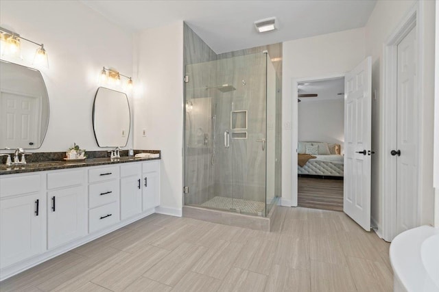 ensuite bathroom with connected bathroom, a sink, a shower stall, and double vanity