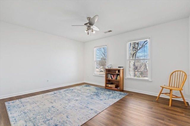 living area featuring baseboards, ceiling fan, visible vents, and dark wood-style flooring