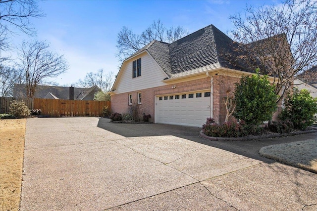 view of side of property with concrete driveway, brick siding, and a shingled roof