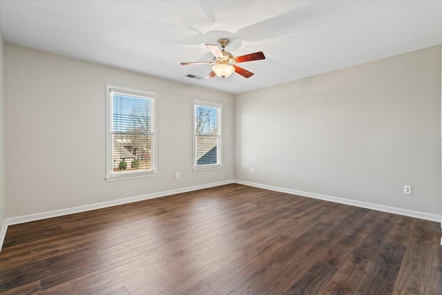 spare room featuring dark wood-style floors, visible vents, baseboards, and a ceiling fan