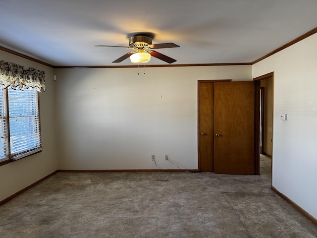 unfurnished room featuring ornamental molding, carpet, baseboards, and a ceiling fan