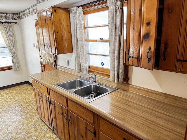 kitchen with a wealth of natural light, baseboards, light countertops, and a sink