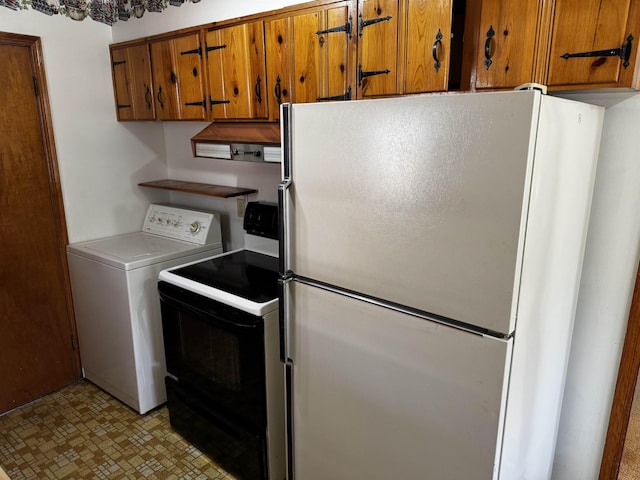 kitchen with washer / dryer, range with electric cooktop, brown cabinets, freestanding refrigerator, and light countertops