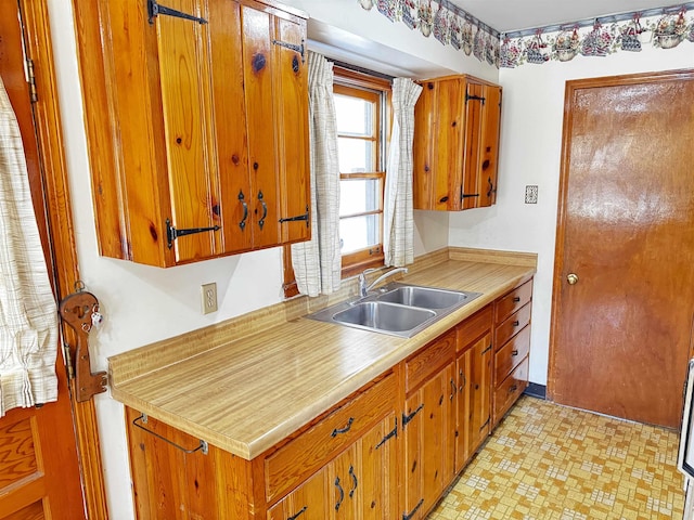 kitchen featuring brown cabinets, light floors, light countertops, and a sink