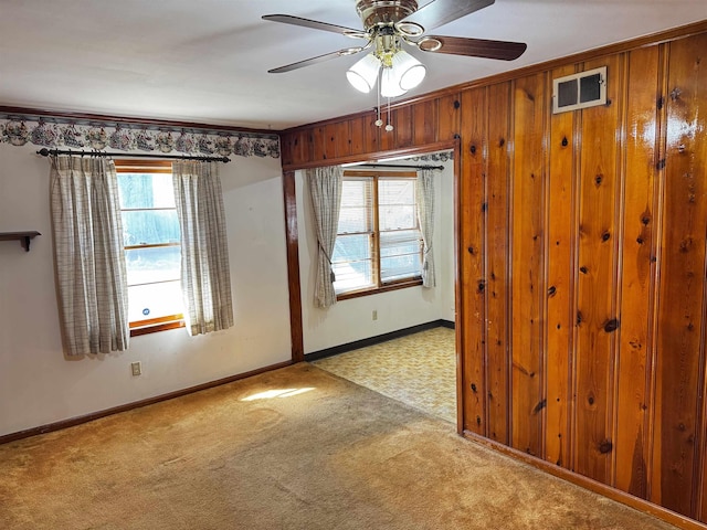 carpeted spare room with visible vents, ceiling fan, and baseboards