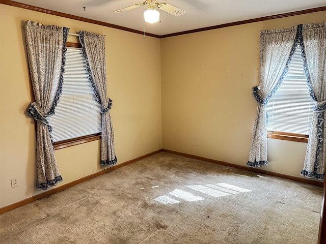 carpeted empty room featuring baseboards, ceiling fan, and crown molding