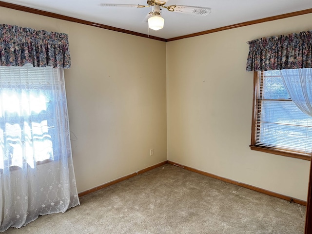 carpeted spare room featuring baseboards, ornamental molding, and a ceiling fan