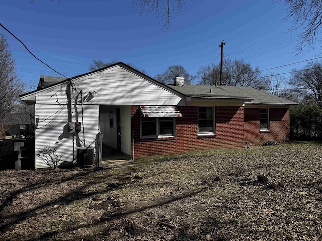 rear view of property with brick siding and a chimney