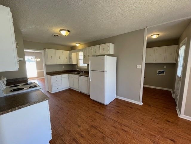 kitchen with white appliances, dark wood-style flooring, dark countertops, and a wealth of natural light