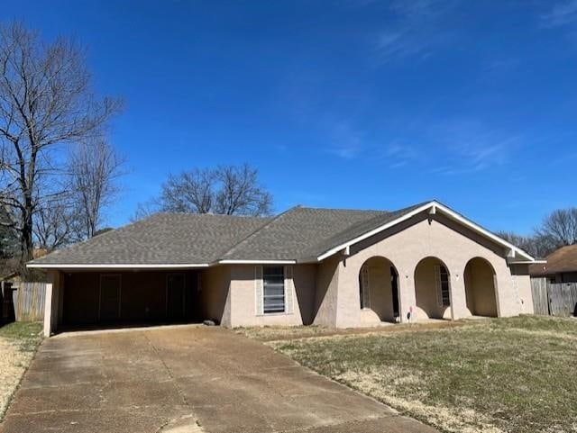 ranch-style house featuring a garage, driveway, a front lawn, and stucco siding