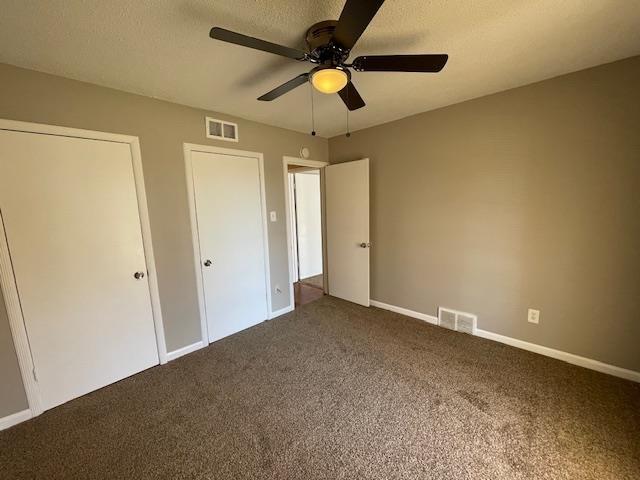 unfurnished bedroom with a textured ceiling, carpet flooring, and visible vents