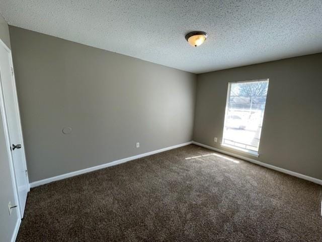 unfurnished room with a textured ceiling, dark carpet, and baseboards