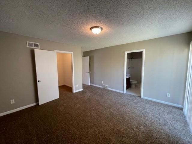 unfurnished bedroom featuring visible vents, a spacious closet, baseboards, and a textured ceiling