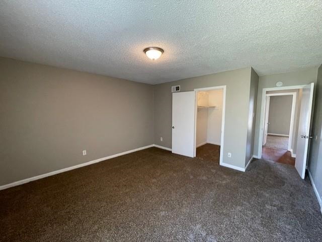 unfurnished bedroom featuring carpet floors, a walk in closet, a closet, visible vents, and baseboards