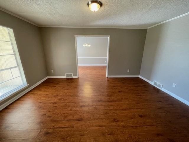 empty room featuring dark wood-style floors, ornamental molding, visible vents, and baseboards