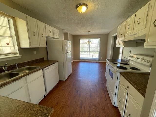 kitchen with dark countertops, white cabinets, a sink, white appliances, and under cabinet range hood