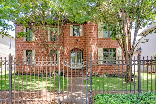 view of front of home featuring a fenced front yard, a front yard, a gate, and brick siding