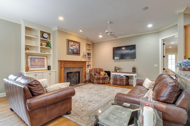 living room with light wood finished floors, a fireplace, ornamental molding, and built in features
