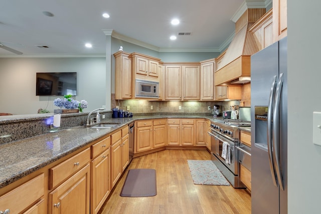 kitchen featuring light brown cabinetry, appliances with stainless steel finishes, dark stone countertops, and light wood-style floors