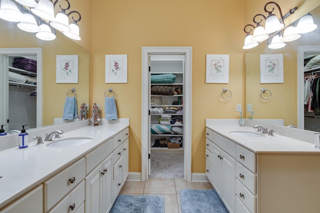 full bath with a walk in closet, two vanities, a sink, and tile patterned floors