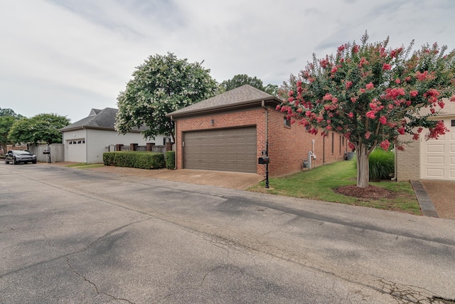 view of home's exterior featuring a shingled roof, brick siding, a yard, and a garage