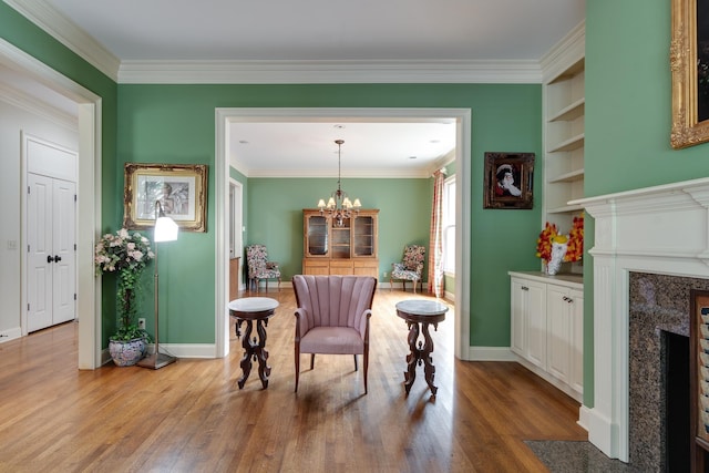 sitting room with built in shelves, a notable chandelier, a premium fireplace, wood finished floors, and baseboards